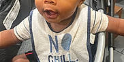 Omri joined the competition — help win amazing prizes! baby, child, stroller, bib, clothing, cute, face, pigtails, infant, sitting, expression, curious, black_hair, indoor, person, young_child, closeup, adorable, playful, portrait