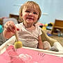Gracelynn is registered to the contest to win money with this photo: art_activity, background_blur, blond_hair, casual_clothing, child, creative, expression, furniture, happy, high_chair, indoor, paintbrush, painting, person, pink_paper, playtime, portrait, smiling, toddler, young_child