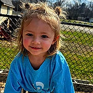 Gracelynn is registered to the contest to win money with this photo: blue_shirt, candid, chainlink_fence, cheeks, child, daylight, eyes, grass, hair_buns, happy, house, outdoor, person, playground, portrait, skin, smile, sunlight, toddler, trees