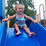 barefoot, blue_slide, casual, child, clothing, daylight, fun, happy, outdoor, park, person, play, playground, recreation, slide, smile, summer, toddler, tree, young_child