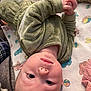 Austin is registered to the contest to win money with this photo: baby, baby_garment, blanket, blue_eyes, child, closeup, clothing, curious, face, green_outfit, hands, head, human, indoor, infant, lying_down, patterned_blanket, portrait, resting, soft_texture