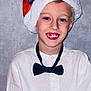 Théo participe au concours pour gagner de l'argent avec cette photo : child, boy, smile, santa_hat, bow_tie, white_shirt, portrait, face, holiday, festive, young, person, blue_eyes, happy, indoor, casual, cute, closeup, celebration, background