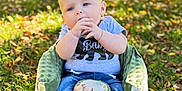 Kole is registered to the contest to win money with this photo: baby, child, outdoor, grass, leaves, seat, green, blue_jeans, socks, hand, face, cute, sunlight, nature, infant, clothing, sitting, portrait, young, curious