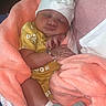 Saniah is registered to the contest to win money with this photo: baby, sleeping, blanket, hat, yellow_clothing, floral_pattern, bracelet, sock, cozy, infant, cute, peaceful, hand, wrapped, soft_texture, newborn, resting, indoors, person, portrait