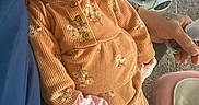 Saniah is registered to the contest to win money with this photo: baby, child, infant, smiling, orange_outfit, floral_pattern, person, hand, baby_swing, carpet, indoor, comfort, cute, resting, lap, clothing, warm, happy, portrait, cozy