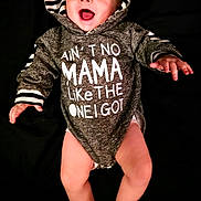 Arimythel is registered to the contest to win money with this photo: baby, hoodie, smiling, happy, infant, clothing, cute, child, portrait, apparel, expression, black_background, hood, one_piece, baby_legs, baby_hands, joy, casual_wear, indoor, face