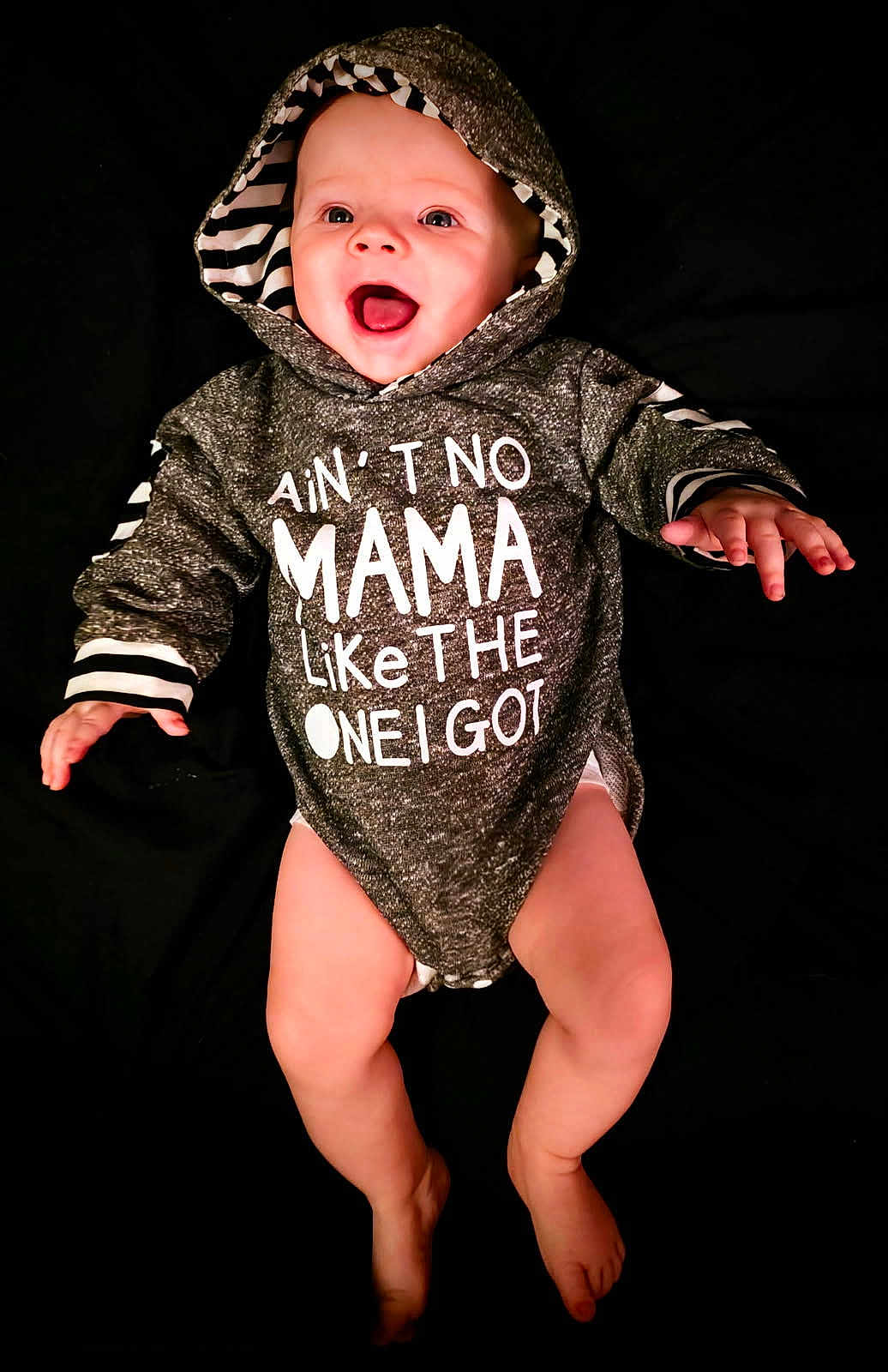 Arimythel is registered to the contest to win money with this photo: baby, hoodie, smiling, happy, infant, clothing, cute, child, portrait, apparel, expression, black_background, hood, one_piece, baby_legs, baby_hands, joy, casual_wear, indoor, face