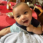 Malcolm participe au concours pour gagner de l'argent avec cette photo : baby, smiling, infant, blanket, table, bottle, cup, chair, dining_room, happy, person, face, clothing, hand, tablecloth, indoor, portrait, holding, young_child, home