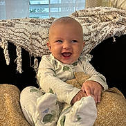 Stetson is registered to the contest to win money with this photo: baby, child, infant, smiling, laughing, portrait, sitting, pajamas, onesie, blanket, cozy, chair, cushion, bedroom, window, curtains, indoor, soft_lighting, happy, feet