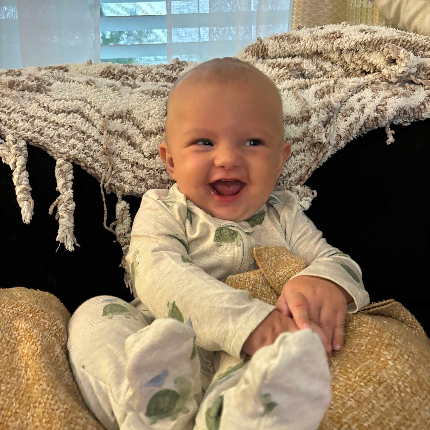 Stetson is registered to the contest to win money with this photo: baby, child, infant, smiling, laughing, portrait, sitting, pajamas, onesie, blanket, cozy, chair, cushion, bedroom, window, curtains, indoor, soft_lighting, happy, feet