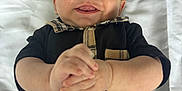 Grayson is registered to the contest to win money with this photo: baby, smiling, infant, black_outfit, plaid, hands, clasped_hands, blanket, white_blanket, text, lying_down, happy, cute, portrait, child, face, head, skin, person, closeup