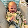 Ames is registered to the contest to win money with this photo: baby, infant, onesie, avocado_pattern, smiling, face, cushion, baby_seat, clothing, child, indoor, cute, happy, person, newborn, soft_toys, blanket, relaxing, comfort, portrait