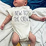 baby, infant, onesie, yellow_booties, blanket, space_pattern, soft_texture, cute, newborn, clothing, knitted_booties, face, lying_down, indoors, child, toddler, expression, cozy, white, casual