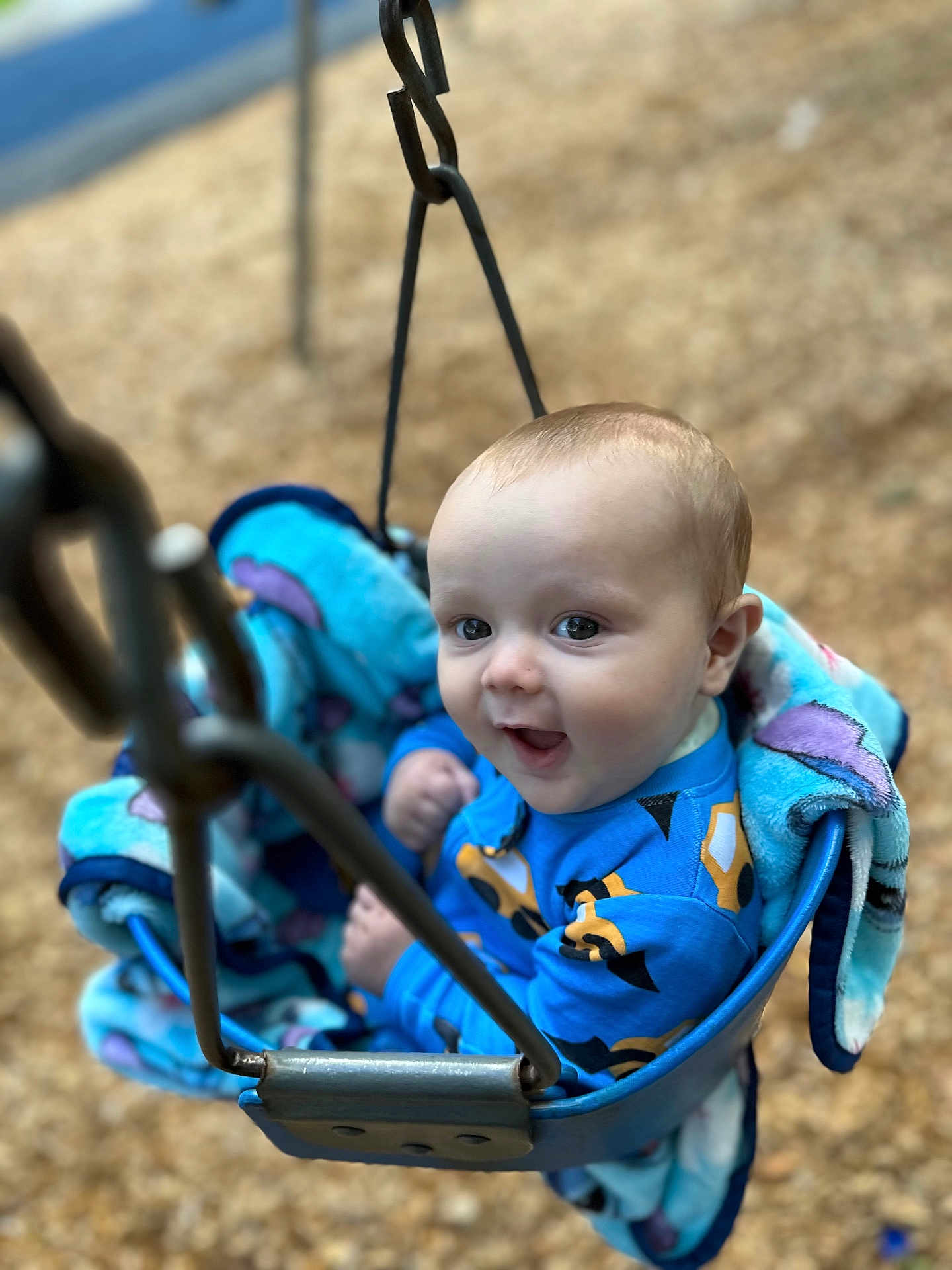Jaimyus is registered to the contest to win money with this photo: baby, child, swing, playground, blanket, blue_clothing, infant, happy, smiling, outdoor, metal_chain, seat, cute, face, fun, park, young_child, play, person, seat_belt