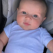 Emmett is registered to the contest to win money with this photo: baby, infant, child, onesie, white_clothing, face, eyes, smile, skin, head, seat, car_seat, cushion, comfort, portrait, closeup, human, cute, young, soft_lighting