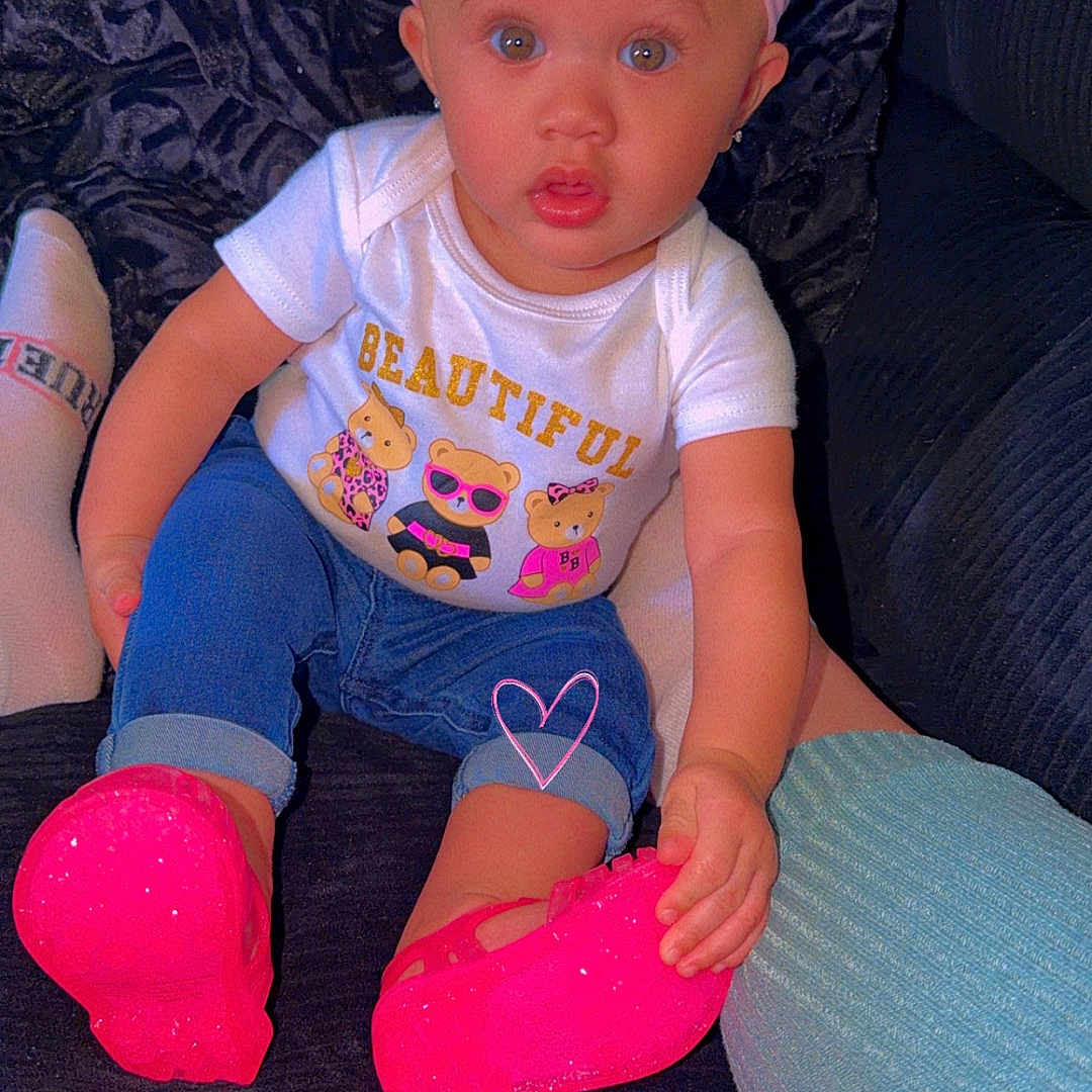 Zoey is registered to the contest to win money with this photo: baby, child, infant, portrait, sitting, couch, bow, pink, shoes, sparkly_shoes, jeans, shirt, bear_design, smiling, wide_eyed, indoor, furniture, closeup, fashion, colorful