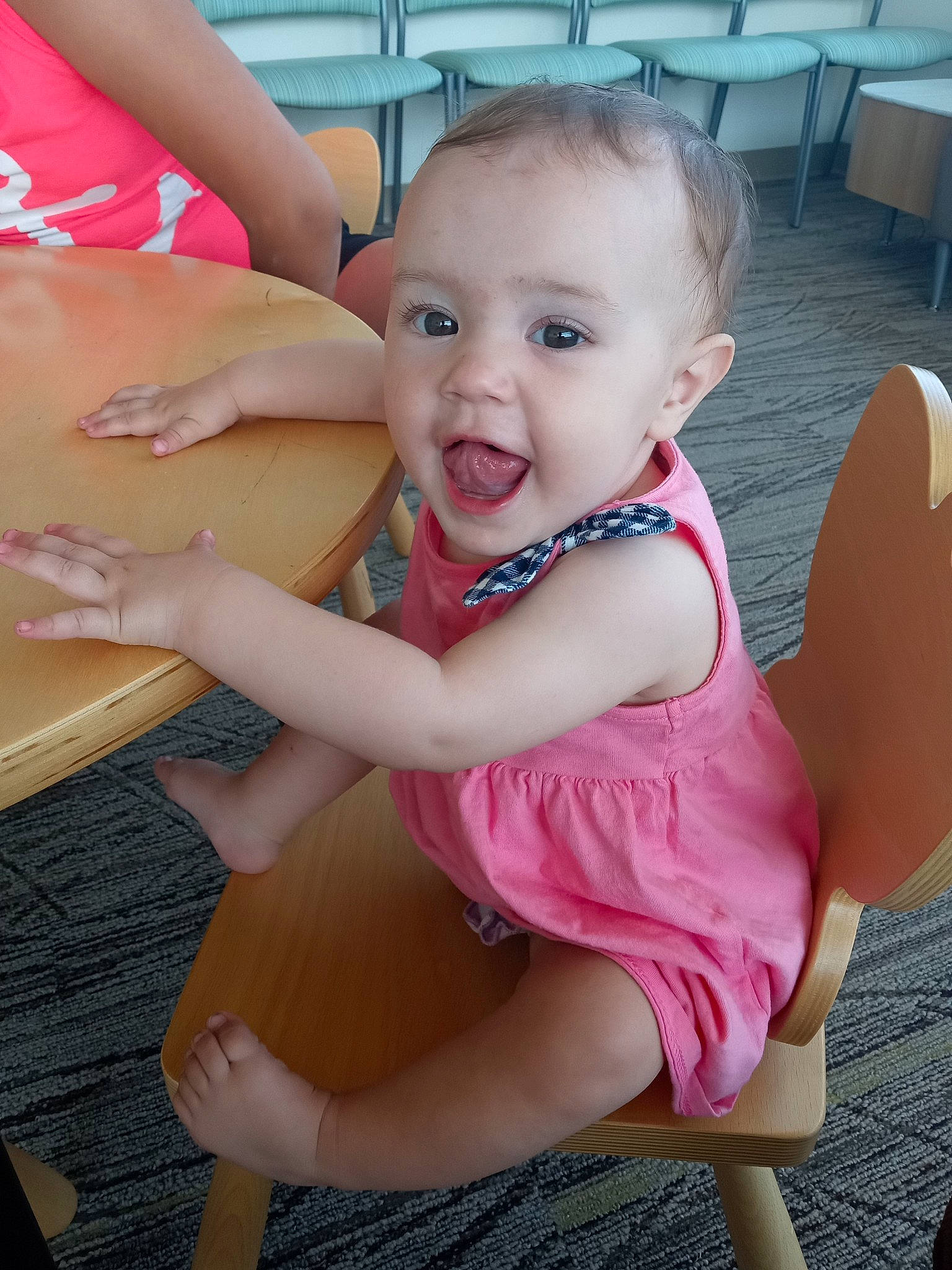 Emerie is registered to the contest to win money with this photo: arm, baby_toddler_clothing, chair, cheek, finger, fun, hand, happy, human_body, human_leg, knee, leg, person, pink, skin, smile, summer, surprise, table, thigh