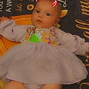 Amelia is registered to the contest to win money with this photo: baby, background_text, blanket, child, clothing, cute, devil_horns, digital_effect, dress, expression, face, feet, indoor, infant, lying_down, person, portrait, purple, soft_lighting, toddler