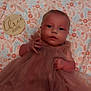 Amelia is registered to the contest to win money with this photo: baby, infant, dress, pink, floral_blanket, wooden_sign, months, portrait, cute, child, laying_down, face, hands, eyes, soft_lighting, fabric, tulle, young, indoors, newborn