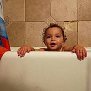 Asher joined the competition — help win amazing prizes! toddler, child, bathtub, bathroom, curly_hair, tiles, hands, peeking, water_droplets, shower_curtain, happy, smiling, skin, face, indoor, young_child, playful, cute, baby, person
