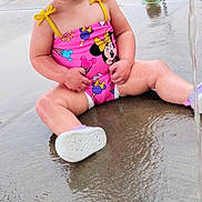 Emily joined the competition — help win amazing prizes! toddler, child, swimsuit, pink, minnie_mouse, sitting, water, wet_surface, play_area, outdoor, smiling, happy, barefoot, summer, fun, young_child, play, cute, water_splash, daytime