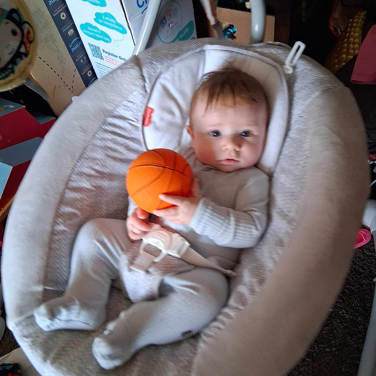 Ely is registered to the contest to win money with this photo: baby, baby_seat, basketball, box, carpet, carrying, child, clothing, expression, face, footwear, furniture, hair, hand, indoor, infant, person, plush, seat, toy