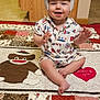 Braxton is registered to the contest to win money with this photo: baby, helmet, smiling, indoor, quilt, patchwork, sock_monkey, heart, love_ya, patterned_clothing, child, floor, carpet, wooden_cabinet, cute, infant, sitting, happy, playful, home