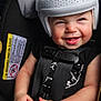 baby, child, helmet, car_seat, car_interior, smiling, happy, clothing, blanket, seatbelt, infant, safety, hands, headgear, cute, person, portrait, indoor, car, seat