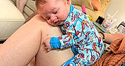 Hudson is registered to the contest to win money with this photo: adult, baby, casual, clothing, comfort, couch, dog, family, hand, home, indoor, leg, living_room, man, nap, pajamas, pet, relaxing, sleeping, superhero