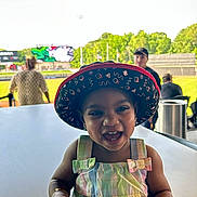 Harmony joined the competition — help win amazing prizes! accessory, baseball_field, bucket_hat, casual, child, colorful_clothing, daylight, dress, fashion, greenery, happy, hat, outdoor, people, person, portrait, smiling, stadium, table, toddler