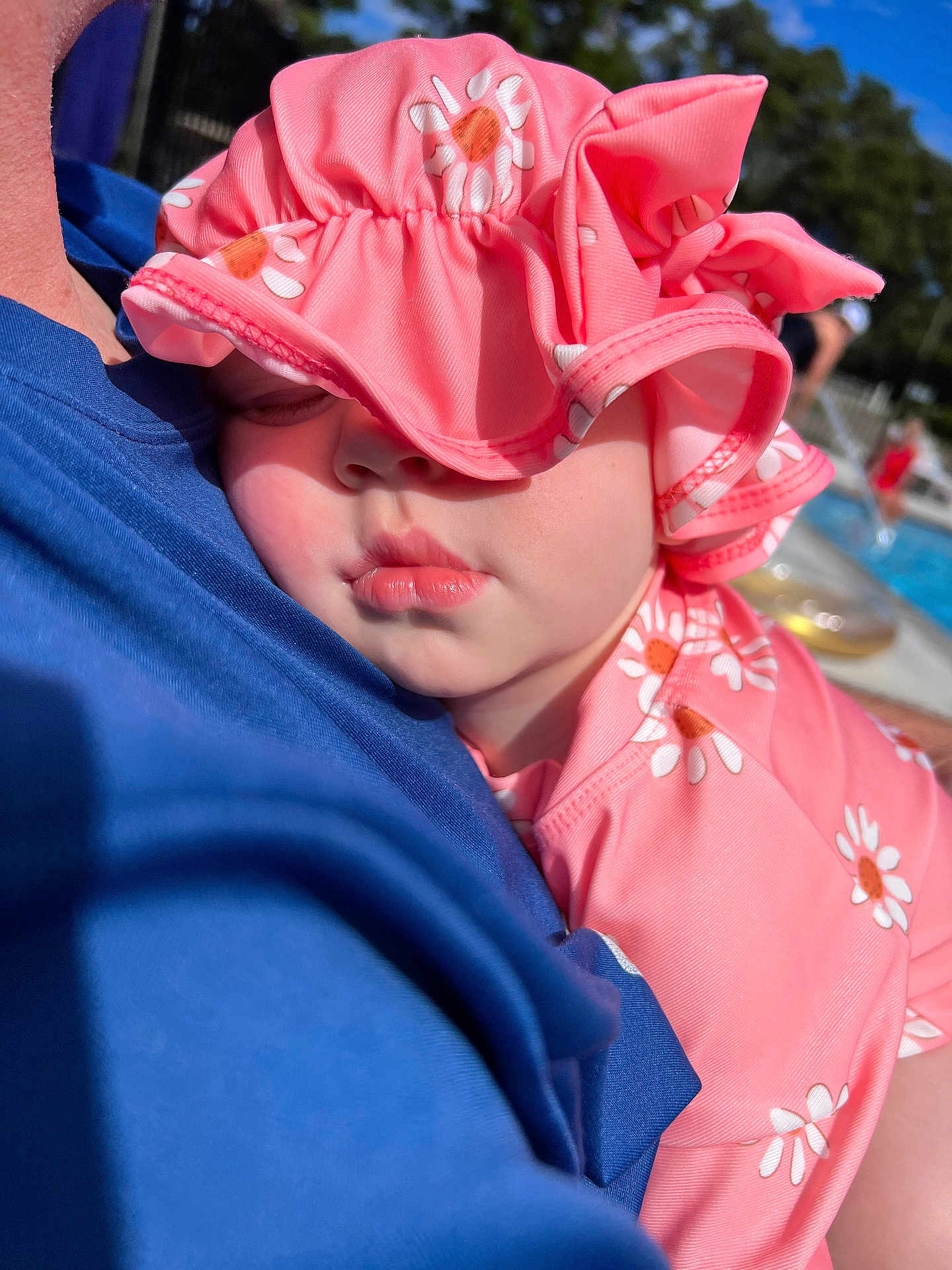 Grace is registered to the contest to win money with this photo: baby, child, sleeping, pink_hat, pink_clothing, daisy_pattern, close_up, outdoor, sunlight, pale_skin, person, portrait, resting, cute, summer, poolside, soft_light, headwear, face, peaceful