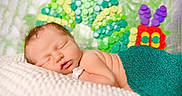 Yasmine is registered to the contest to win money with this photo: newborn, baby, sleeping, blanket, teal, knitted, caterpillar, colorful, soft, peaceful, infant, cute, portrait, child, resting, indoors, closeup, skin, head, face
