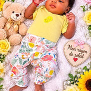 Marlucia is registered to the contest to win money with this photo: baby, child, infant, portrait, lying_down, smiling, floral, flowers, sunflowers, roses, daisies, teddy_bear, blanket, yellow_shirt, floral_pants, heart_sign, indoors, colorful, cute, photography