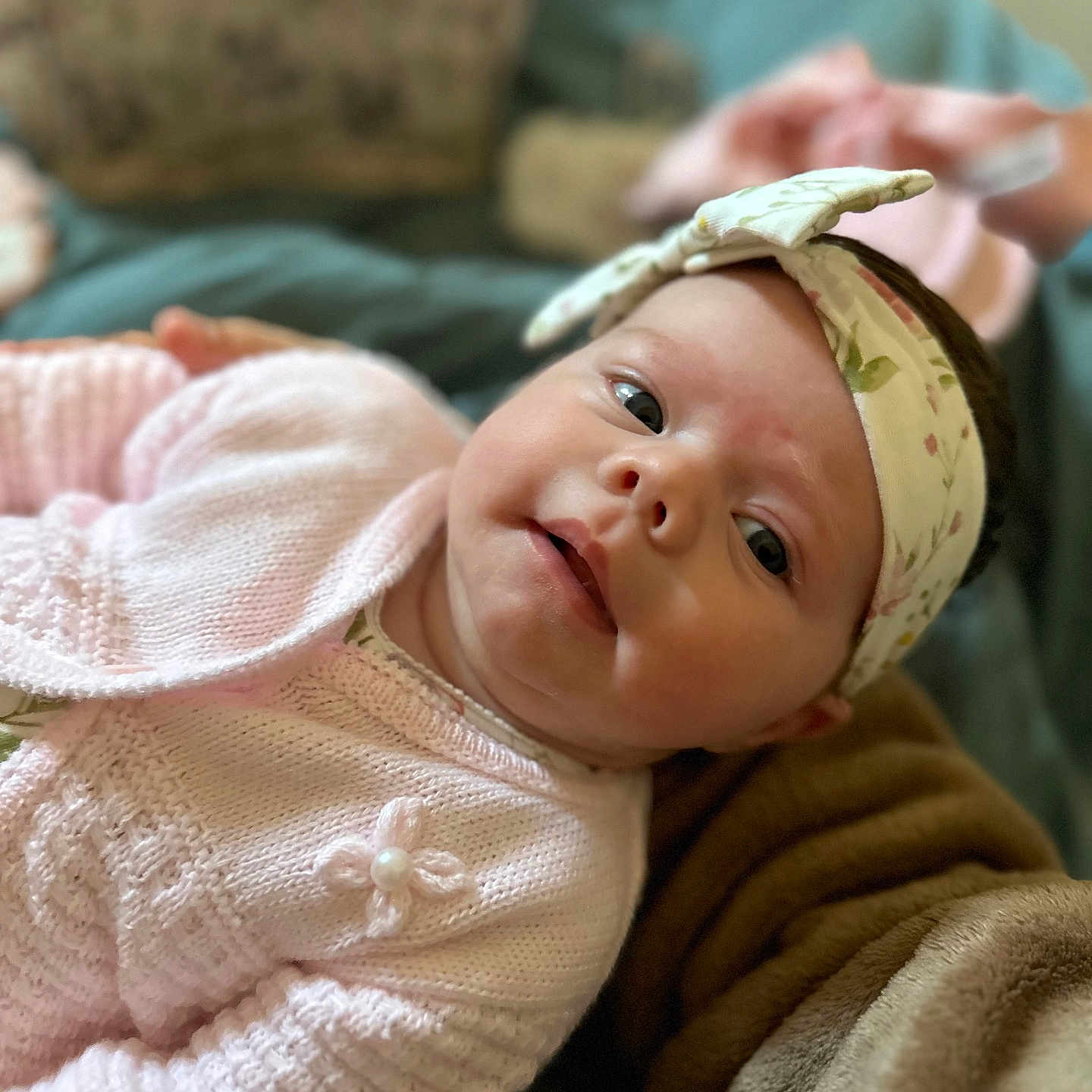 Freya-Joy is registered to the contest to win money with this photo: baby, blanket, child, closeup, cozy, cute, expression, fabric, face, headband, indoor, infant, knitwear, lying_down, person, pink_sweater, portrait, skin, soft_lighting, young