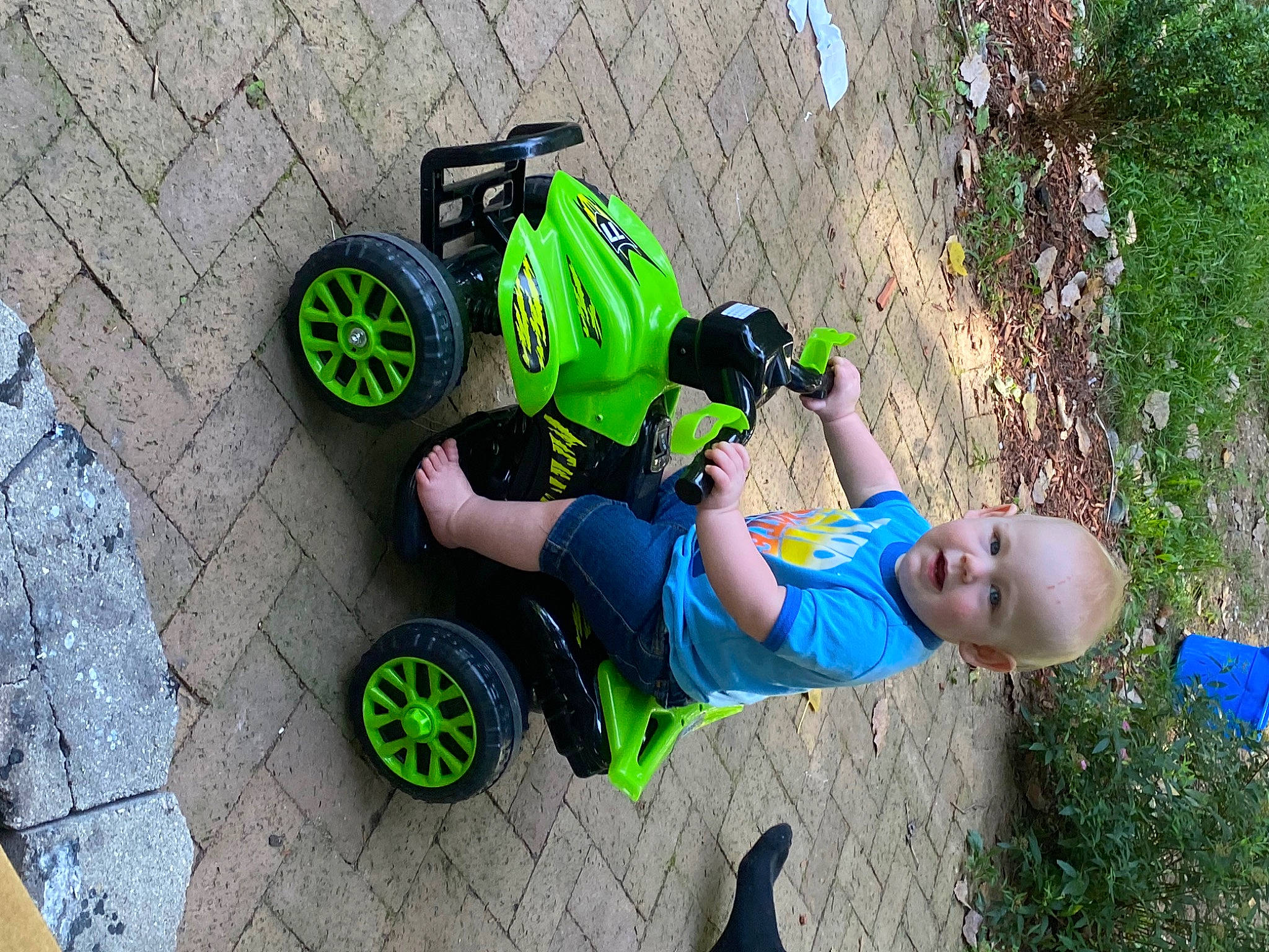 Jessie is registered to the contest to win money with this photo: asphalt, auto_part, automotive_tire, automotive_wheel_system, bicycle_tire, fun, grass, green, helmet, leisure, motor_vehicle, person, public_space, recreation, rolling, sidewalk, tire, toddler, tread, vehicle