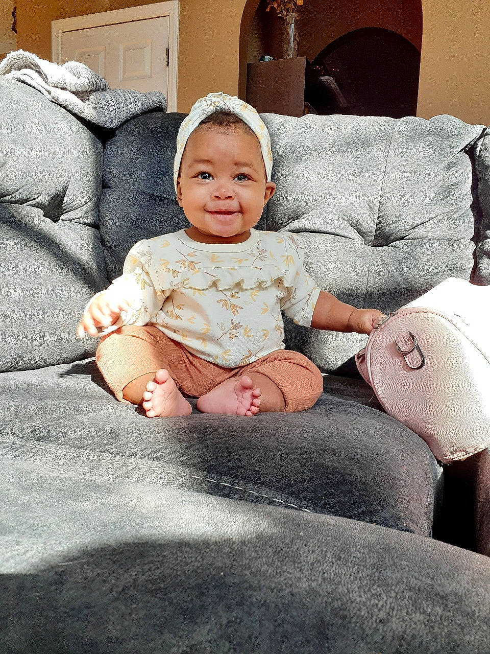 Alana is registered to the contest to win money with this photo: baby, baby_toddler_clothing, child, comfort, couch, fashion_accessory, flash_photography, foot, fun, happy, human_leg, joy, lap, living_room, person, room, sitting, smile, sock, thigh