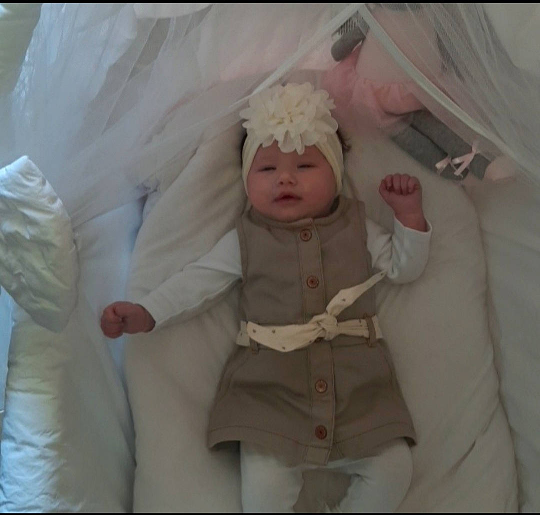 Tess a rejoint le concours — aidez-le/la à gagner de superbes lots ! baby, baby_products, baby_safety, baby_sleeping, baby_toddler_clothing, child, comfort, fashion_accessory, fur, gesture, hair_accessory, happy, headwear, linens, peach, person, pink, room, sleeve, textile