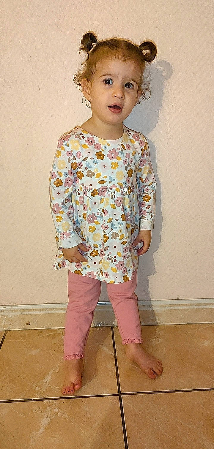 Lina participe au concours pour gagner de l'argent avec cette photo : arm, baby_toddler_clothing, cheek, child, face, fashion_design, head, human_body, neck, outerwear, pattern, peach, person, pink, shoulder, skin, sleeve, t_shirt, toddler, vintage_clothing