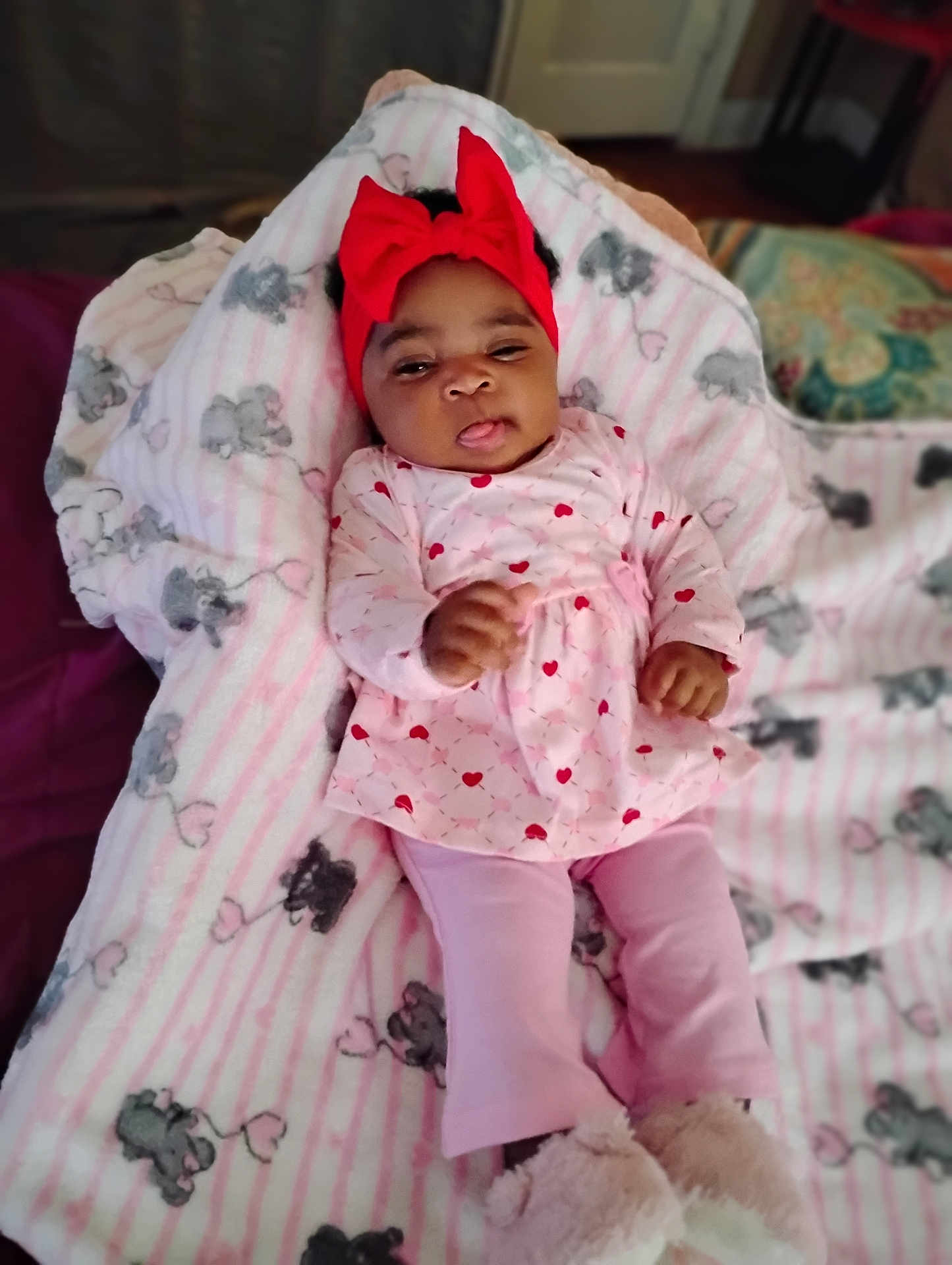 A'Leysa Tayonna joined the competition — help win amazing prizes! baby, child, infant, blanket, elephant_print, pink_clothing, headband, red_bow, lying_down, cozy, soft_toys, cute, tongue_out, indoor, carpet, floor, furniture, room, legs, feet