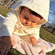 Larissa joined the competition — help win amazing prizes! baby, blanket, child, curious, cute, daylight, exploring, grass, hoodie, infant, nature, outdoor, park, person, portrait, sitting, soft_texture, sunlight, warm_clothing, white_clothing