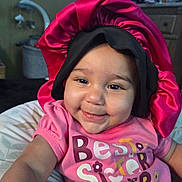 Braylee is registered to the contest to win money with this photo: baby, smile, child, pink_shirt, bonnet, indoor, face, portrait, cute, happy, infant, clothing, person, headwear, sitting, home, closeup, young_child, cheerful, baby_girl