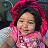 baby, baby_girl, bonnet, cheerful, child, closeup, clothing, cute, face, happy, headwear, home, indoor, infant, person, pink_shirt, portrait, sitting, smile, young_child