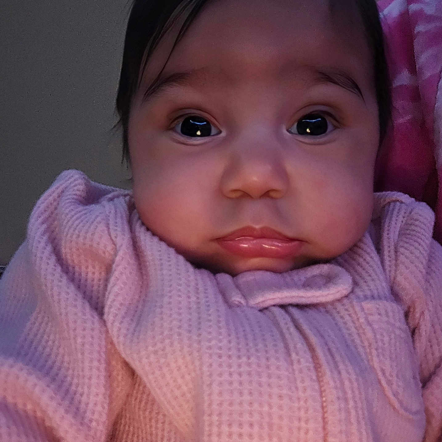 Braylee joined the competition — help win amazing prizes! baby, infant, face, portrait, pink_clothing, close_up, expression, child, cute, indoors, blanket, soft_lighting, young_child, person, newborn, warm_clothing, sitting, head, skin, eyebrows