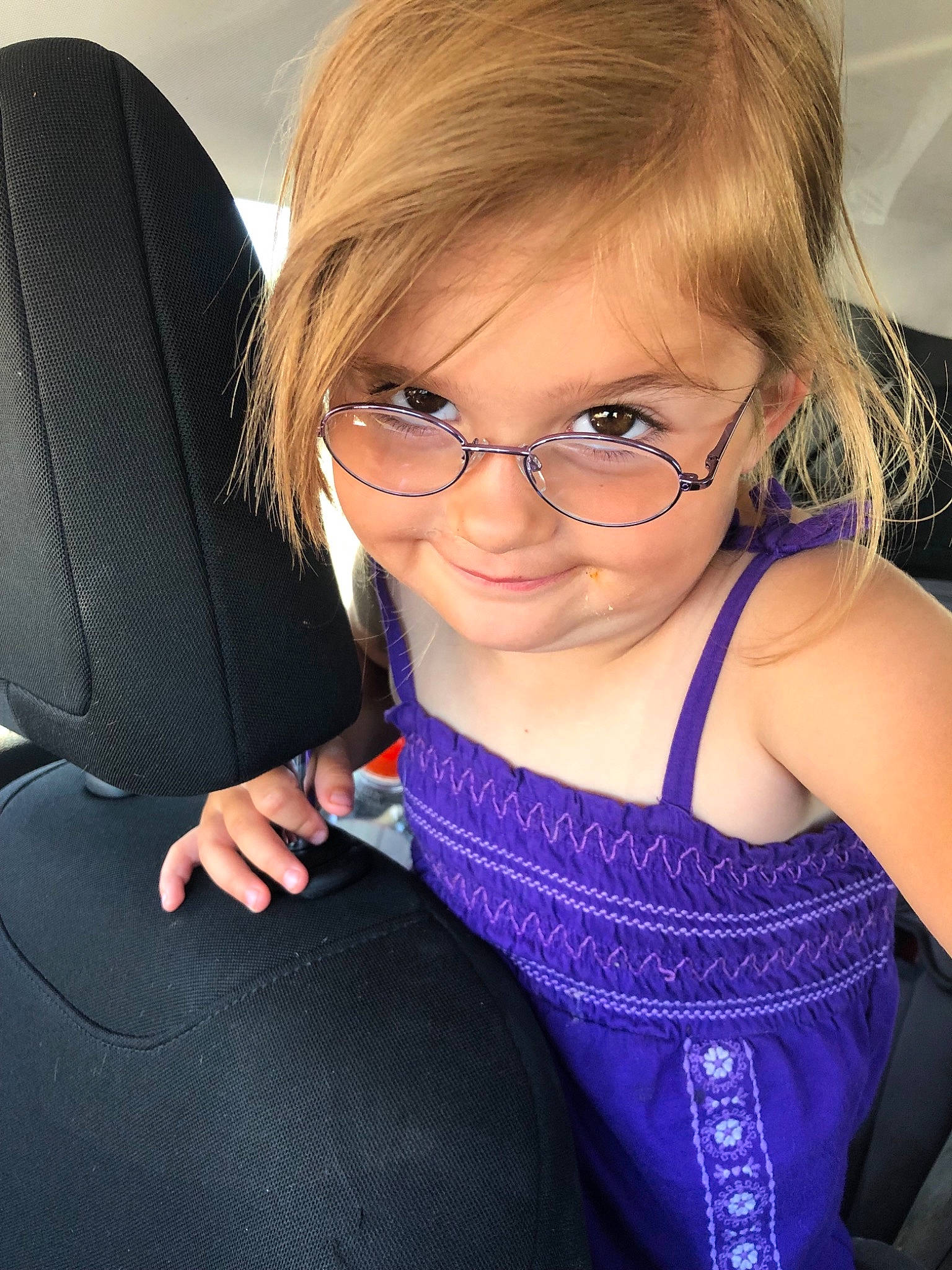 Temperance is registered to the contest to win money with this photo: arm, blond, child, child_model, eyewear, glasses, hair, neck, person, personal_protective_equipment, purple, seat_belt, shoulder, smile