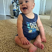Christopher is registered to the contest to win money with this photo: baby, child, smiling, sitting, carpet, indoor, tank_top, shorts, vacuum_cleaner, door, floor, happy, person, skin, foot, hand, furniture, home, room, expression