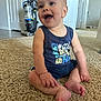 baby, child, smiling, sitting, carpet, indoor, tank_top, shorts, vacuum_cleaner, door, floor, happy, person, skin, foot, hand, furniture, home, room, expression