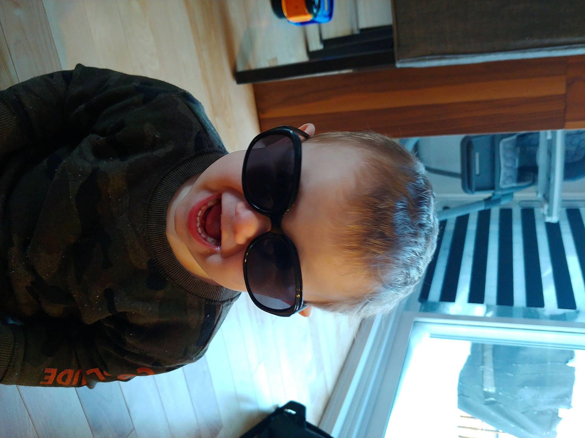 Liam participe au concours pour gagner de l'argent avec cette photo : black_hair, child, chin, comfort, eyewear, fun, hat, nose, person, personal_protective_equipment, room, smile, sunglasses, toddler, vacation, vision_care, wood