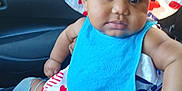 Isabella joined the competition — help win amazing prizes! baby, child, hat, bib, clothing, person, indoor, car, seat, hand, face, skin, hair, beads, pattern, heart, stars, blue, red, white