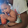 Isabella is registered to the contest to win money with this photo: baby, child, adult, diaper, cup, drink, indoor, person, holding, clothing, tshirt, shorts, hair, hand, face, floor, door, fan, furniture, home