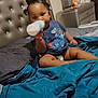 Isabella is registered to the contest to win money with this photo: baby, bottle, bed, blanket, blue_clothing, child, dinosaur_print, furniture, hair, indoors, infant, person, pillow, sitting, sleepwear, toddler, toy, wall, young_child, room